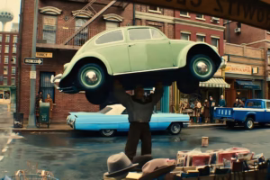 The Thing from Fantastic Four: First Step lifts a green car over his head in a dramatic scene set on a city street, with onlookers in the background.