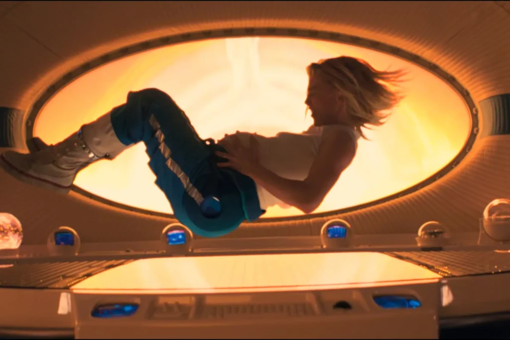 Silhouette Of Sue Storm Playing Guitar Inside Spaceship With Circular Window Showing Orange Sunset In The Fantastic Four: First Steps