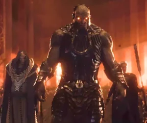 Darkseid Standing In Armor With Glowing Red Eyes In Fiery Throne Room On Apokolips With Followers Behind Him
