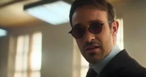 Charlie Cox as Matt Murdock in a suit and red tinted glasses in Daredevil Born Again Season 2